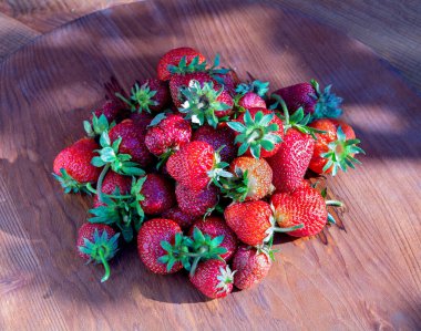 Bahçedeki ahşap masada bir sürü sulu çilek var. Yakın plan..