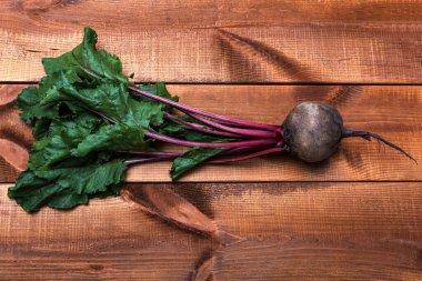 Tahta arka planda yeşil yapraklı taze kırmızı pancarlar. Yakın plan.