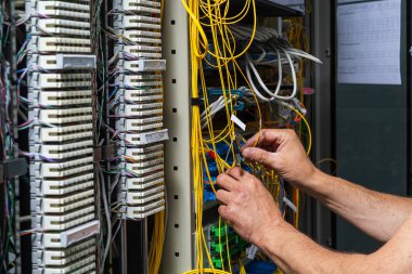 Telekomünikasyon panelinden geçen bir teknisyenin elleri.
