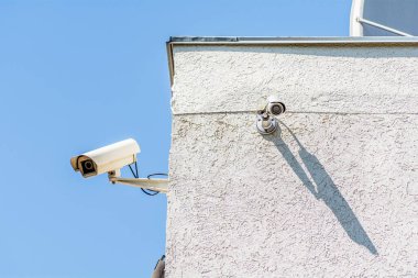 Binanın köşesinde gökyüzünün arka planına karşı iki güvenlik kamerası var. Güvenli şehir kavramı.