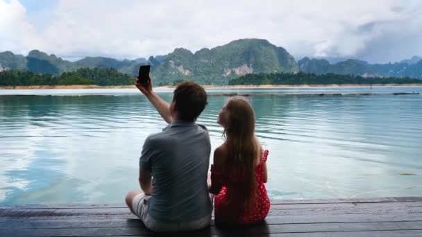 Linda pareja romántica filmando blog o chat de vídeo en el teléfono móvil en Amazing Lake — Vídeos de Stock