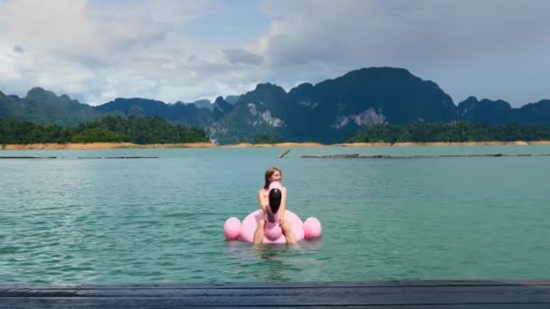 Felice donna attraente in vacanza sedersi su Pink Flamingo galleggiante a Blue Lake — Video Stock