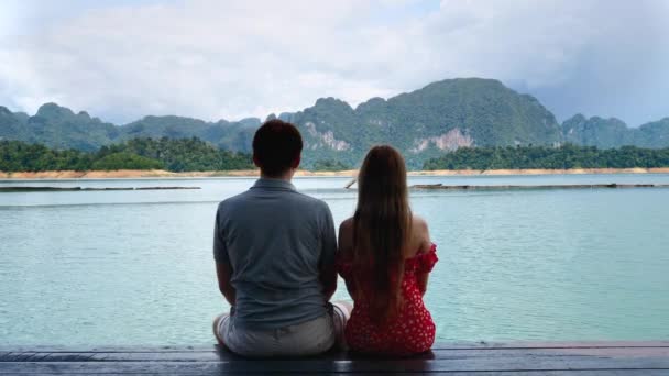 デートのカップル一緒に湖の橋の上に座ると女性は肩に頭を置く — ストック動画