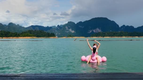 Divertimento sorridente da mulher sobre no Flamingo inflável cor-de-rosa, relaxe, bronzear-se e apreciar — Vídeo de Stock