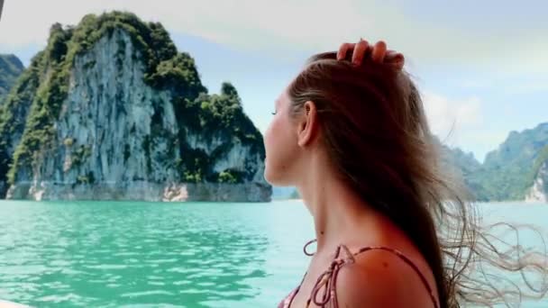 Mujer turista sonriente sentada en el barco, endereza el cabello largo y disfruta de la naturaleza — Vídeos de Stock