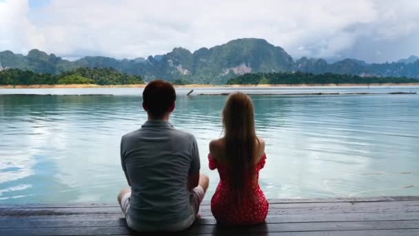 Pár na rande sedět spolu na jezeře most, muž flirtování a stále tvrdší facka — Stock video