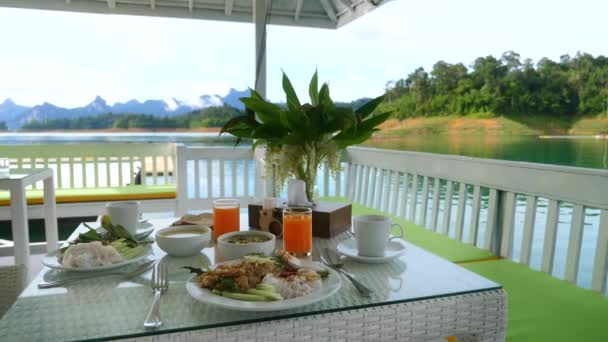 Desayuno para dos en la naturaleza en el restaurante al aire libre en el lago verde con montañas — Vídeo de stock