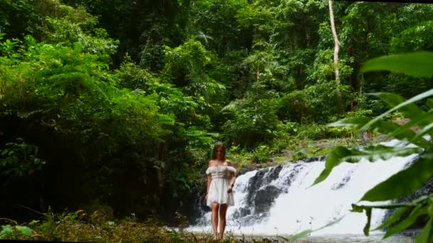 Turystka w białej sukience spaceruje boso w pobliżu Cascade Tropical Waterfall — Wideo stockowe