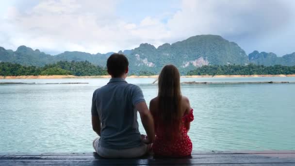 Pár na rande sedět spolu na jezeře most, muž flirtování a získávání legrační facka — Stock video