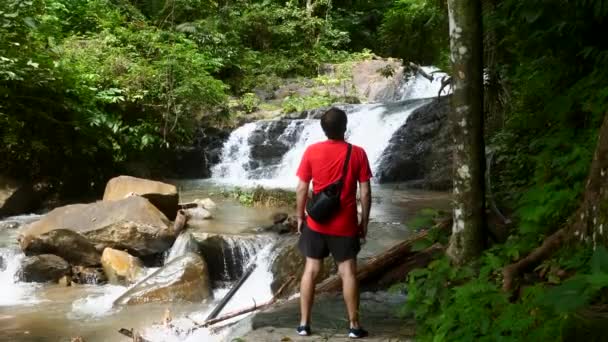 Turista viajando na selva com rochas e cachoeira, Aventura em viagem — Vídeo de Stock