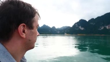 Happy Smiling Man Sitting on Boat and Sailing on Morning Lake with Mountain