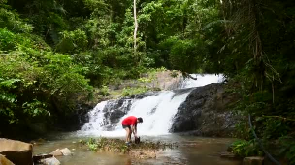 Homem viajante desfrutando de cachoeira, saco impermeável aberto e tomar telefone móvel — Vídeo de Stock