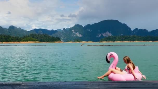 Mujer torpe divertirse, tontear y tratar de nadar en flamenco inflable rosa — Vídeos de Stock