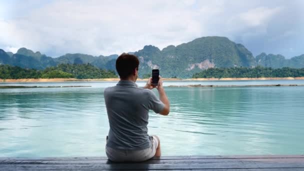Hombre Filmando Blog o Vlog o Video Chat en el teléfono móvil en Amazing Lake — Vídeo de stock