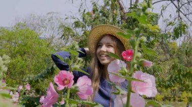 Mutlu Gülümseyen Gezgin Kadın Güneşli bir günde Pembe Çiçeklerle Bahçede Dinleniyor