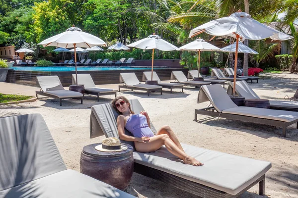 Gyönyörű nő Pihenjen és Napozzon nyaralás Resort medencével és napozóágyakkal — Stock Fotó