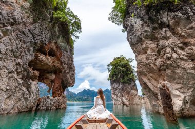 Seyahat eden kadın, Tayland 'daki Khao Sok Parkı' nda ünlü üç kayanın yanında oturuyor.