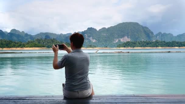 Back View of Man Filming Blog or Vlog on Mobile Phone at Amazing Lake — 비디오