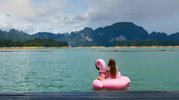 Επιστροφή Προβολή της γυναίκας σε διακοπές Καθιστή και Κολύμβηση σε ροζ επίπλευση Flamingo — Αρχείο Βίντεο
