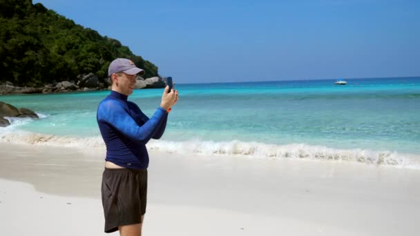 Turista hombre hacer video teléfono móvil en la playa con arena blanca y hermoso mar — Vídeos de Stock
