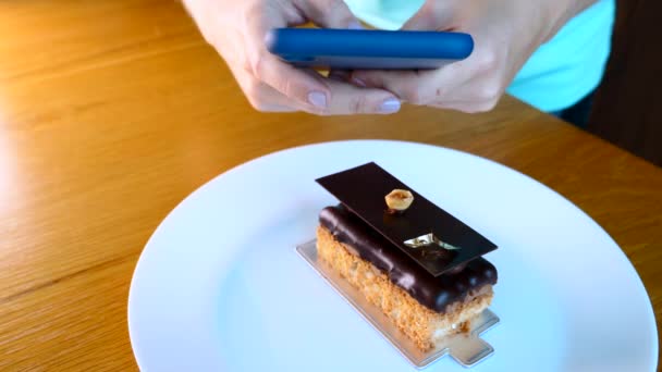 Frauenhand mit Handy fotografiert Opernkuchen-Dessert auf weißem Teller — Stockvideo