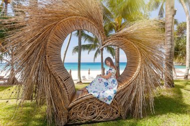 Fotoğrafta oturan Turist Kadın Palmiyeli Hasır Kalp gibi