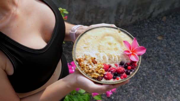 Hände halten Bananen-Frucht-Smoothie-Schüssel mit Beeren und Müsli — Stockvideo