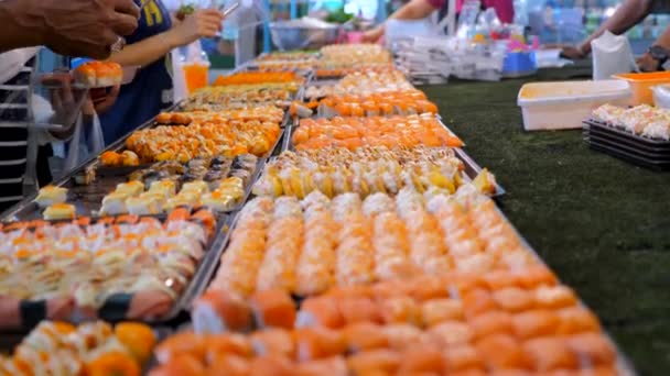 La gente compra comida japonesa en el mercado nocturno. Mercado callejero con sushi fresco — Vídeo de stock