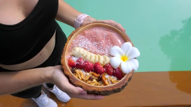Fitness nainen urheiluvaatteissa Pidä tuoretta smoothie-kulhoa tuoreilla mansikoilla — kuvapankkivideo