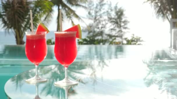 Wassermelonen-Shake-Cocktail in der Nähe von Schwimmbad mit Palmen und Meer im Hintergrund — Stockvideo