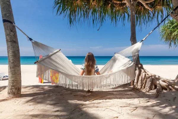 Vista trasera de la mujer de viaje sentada en una hamaca blanca en Sandy Beach — Foto de Stock