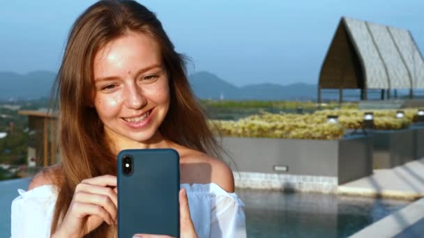 Νεαρή χαμογελαστή γυναίκα με Smartphone Πληκτρολογώντας το μήνυμα ή να κάνει Video Call — Αρχείο Βίντεο