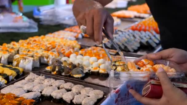 Hombre y mujer eligiendo sushi fresco del mercado nocturno — Vídeo de stock