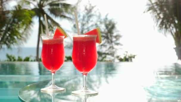 Cocktails à la pastèque près de la piscine avec palmiers et mer en arrière-plan — Video