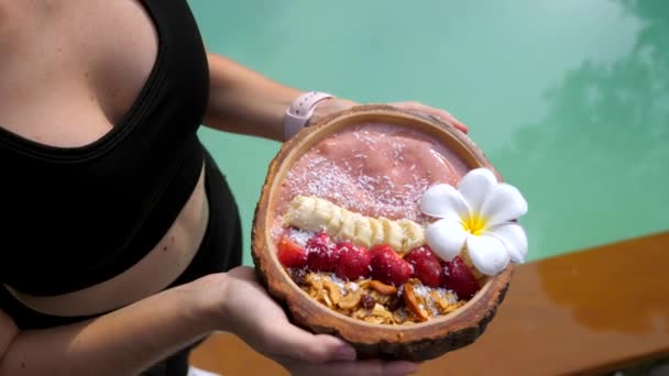 Femeia de fitness în îmbrăcăminte sport ține castron de smoothie vegan cu fructe proaspete — Videoclip de stoc