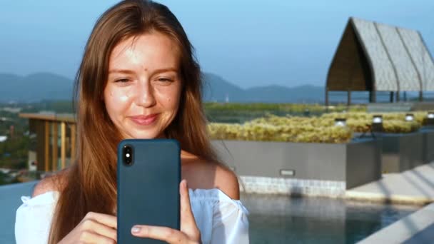 Νεαρή χαμογελαστή γυναίκα με Smartphone Κάνοντας Video Call στο Rooftop του ξενοδοχείου — Αρχείο Βίντεο