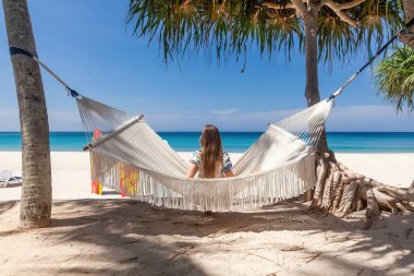 Sandy Beach 'te Beyaz Hamak' ta oturan Gezgin Kadın 'ın Arka Görünümü