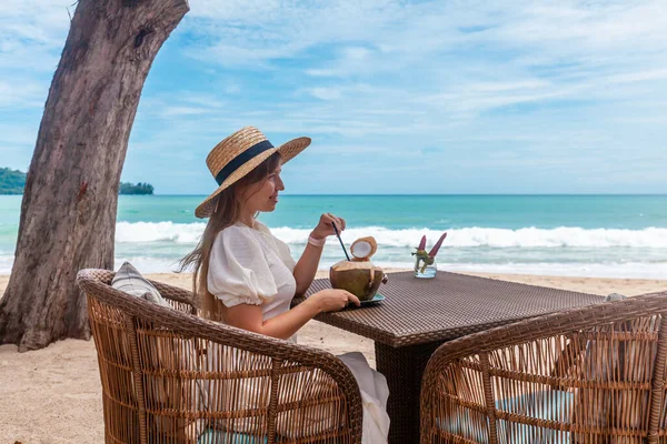 Beyaz elbiseli ve Hasır Şapkalı Kadın Açık Plaj Kafesinde Masada Oturuyor — Stok fotoğraf