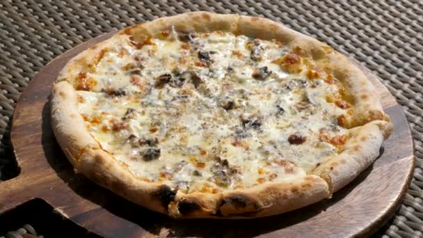 Gros plan de la pizza à la truffe cuite au four sur une assiette en bois dans un café en plein air lors d'une chaude journée ensoleillée — Video