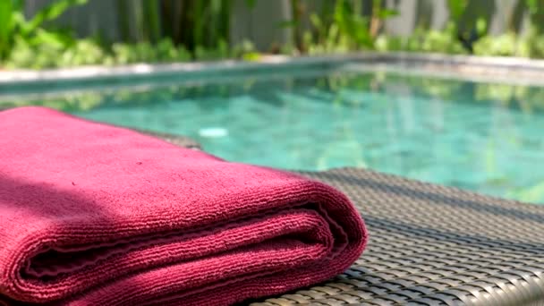 Red Beach Towel Lying on Sunbed near Swimming Pool with Tropical Green — Stock Video