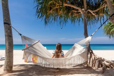 Sandy Beach 'te Beyaz Hamak' ta oturan Gezgin Kadın 'ın Arka Görünümü