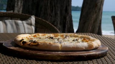 Sıcak Güneşli Gün 'de, açık kafedeki ahşap tabakta fırında mantar pizzasının yakın çekimi.
