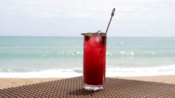 Coctel de bayas rojas frescas en la mesa de playa, mar turquesa desenfocado en el fondo — Vídeo de stock