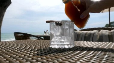 Kadın eli kadehleri buz küpleriyle dolduruyor Tepache içki şişesinden
