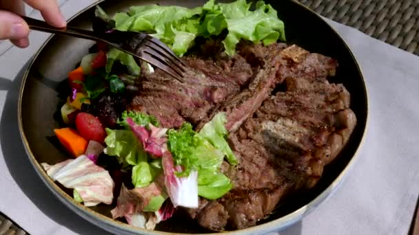 Mano de hombre con tenedor Tome porción de filete de res asado fresco en el restaurante — Vídeo de stock