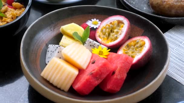 Houten schaal met vers tropisch fruit in Restaurant. Gezond veganistisch ontbijt — Stockvideo