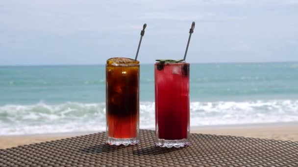 Schöne erfrischende Fruchtcocktails auf dem Tisch am Strand, blaues Meer im Hintergrund — Stockvideo