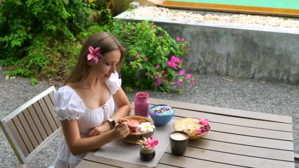 健康的な朝食を食べるスムージーボウル.女はアサイースムージーを食べます,コーヒーを飲みます — ストック動画