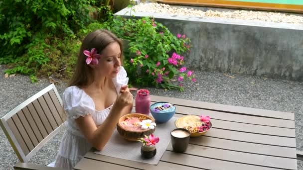 健康的な朝食を食べるスムージーボウル.女はアサイースムージーを食べます,コーヒーを飲みます — ストック動画