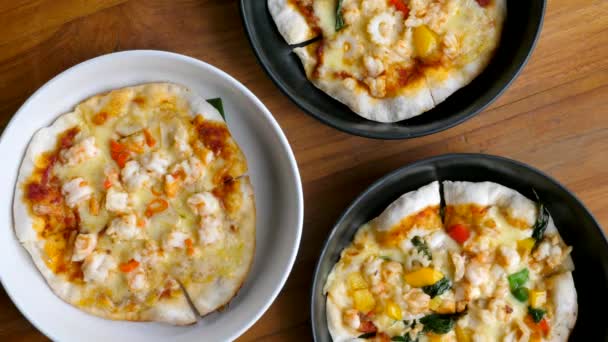 Draufsicht auf das Sortiment an kleinen Pizzen in Tellern auf holzvertäfeltem Hintergrund — Stockvideo